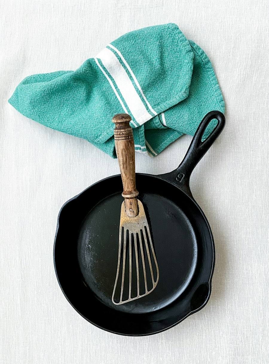 Gietijzeren pan met een vork en een theedoek op tafel