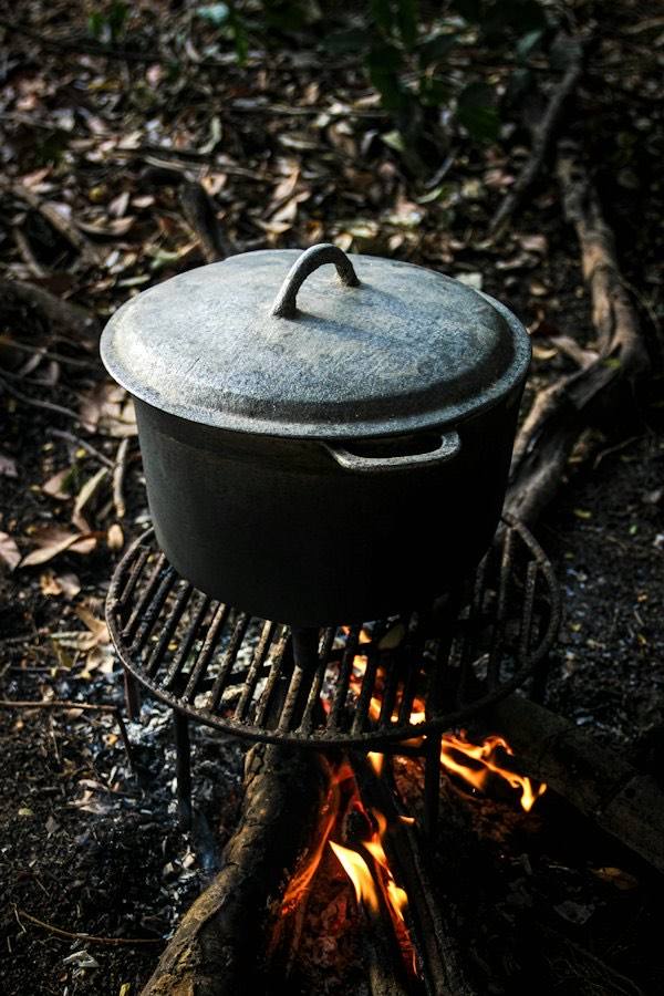 Gietijzeren braadpan met deksel boven een vuur
